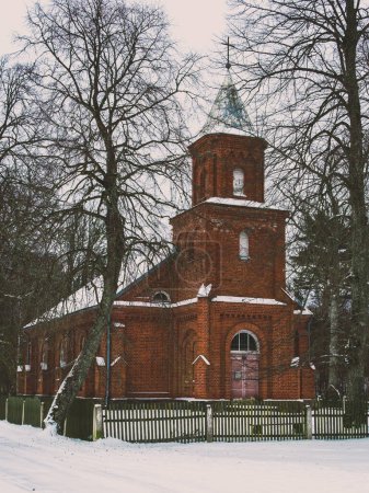 Nestled amidst the wintry landscape, Mikeltornis' small brick church exudes timeless grace, its quaint charm standing as a beacon of hope amidst the cold snowy day.