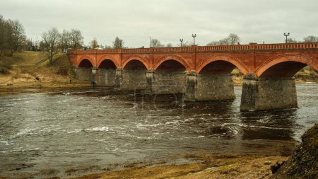 Téléchargez les photos : Alors que les saisons changent et que le temps passe, le pont en brique rouge de Kuldiga demeure un symbole inébranlable de la riche tapisserie culturelle lettone.. - en image libre de droit