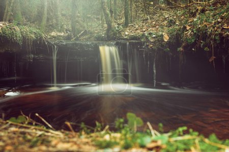 Der schnelle Fluss des Olupite-Wasserfalls, der lange belichtet wird, verwandelt sich in ein faszinierendes Schauspiel, eine Ode an die ungezähmte Schönheit Lettlands.