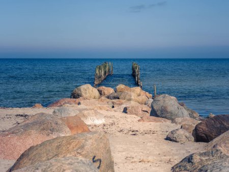 Auf dem sandigen Pfad wandert man durch die Schönheit der lettischen Küste und folgt den Spuren der Geschichte bis zu einem in die Jahre gekommenen Dock, das Wächter gegen die Zeit ist.