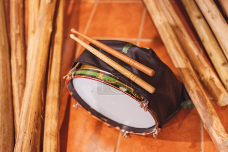 Two drumsticks on an Easter drum, resting on the ground next to wooden logs