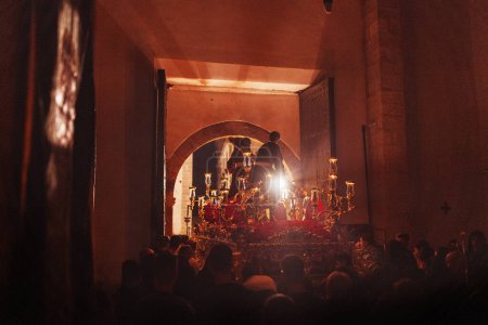 Téléchargez les photos : Procession de la Semaine Sainte à l'intérieur d'une église sombre marchant dehors la nuit entourée par beaucoup de gens. - en image libre de droit