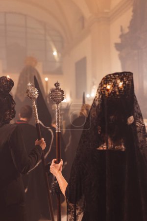 Foto de Mujeres en procesión vestidas de negro con caña metálica en las manos - Imagen libre de derechos