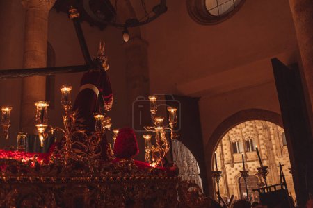 Téléchargez les photos : Procession de la Semaine Sainte à l'intérieur d'une église sombre marchant dehors la nuit entourée par beaucoup de gens. - en image libre de droit