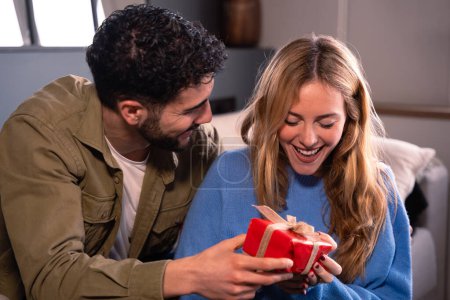 Téléchargez les photos : Portrait de jeune homme et femme heureux et souriant embrassant et tenant boîte cadeau rouge. - en image libre de droit