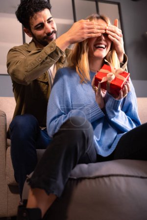 Téléchargez les photos : Beau jeune couple à la maison profiter du temps ensemble tout en célébrant la Saint-Valentin donnant des cadeaux - en image libre de droit