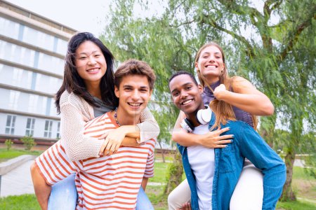 Téléchargez les photos : Les jeunes élèves s'amusent à porter leurs amis les bras levés en regardant la caméra. - en image libre de droit