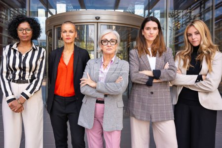 Photo for Five businesswomen standing side by side with their arms crossed looking at the camera angry. Suitable for team, friendship and diversity concepts. - Royalty Free Image