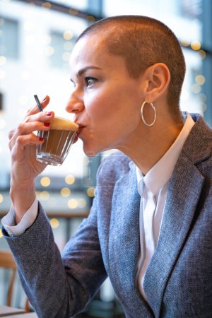 Foto de Vista lateral Businesswoman en un café de moda beber café. Hermosa modelo caucásico Reflejos de las ventanas. - Imagen libre de derechos