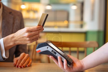 Foto de Primer plano irreconocible Mano de una joven que tiene una tarjeta de crédito y realiza una transacción de pago. - Imagen libre de derechos