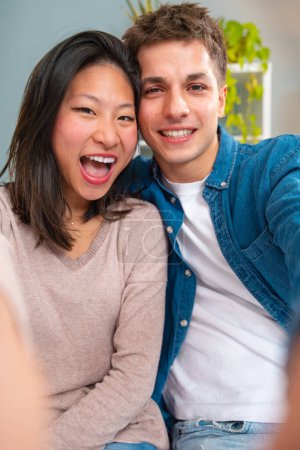 Foto de Jóvenes sonriendo amigos multirraciales tomando una selfie en la sala de estar. Conceptos de juventud, estilo de vida de los pueblos, diversidad, vida urbana - Imagen libre de derechos