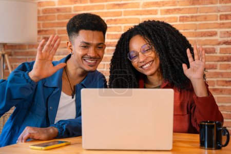 Photo for Multiethnic couple using computer making each other smile at home, Latino boyfriend and African American girlfriend on social media.Indoors - Royalty Free Image
