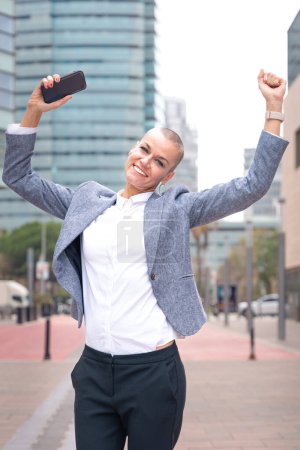 Photo for Caucasian mid adult woman pointing arms up with cell phone in hand, laughing looking at camera Woman showing signs. - Royalty Free Image