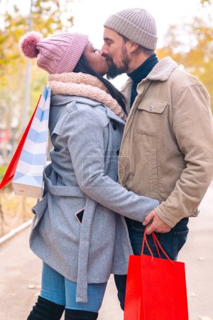 Téléchargez les photos : Beau couple faisant du shopping en ville marchant et tenant des sacs à provisions à l'extérieur. Amoureux - en image libre de droit