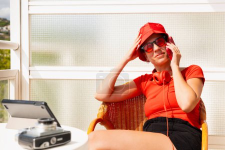 Foto de Elegante mujer joven sonriendo haciendo una llamada con un teléfono celular con gafas y sombrero rojo Una hermosa mujer caucásica con sombrero rojo y gafas sonriendo al aire libre. - Imagen libre de derechos