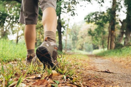 Téléchargez les photos : Pieds d'un adulte portant des bottes pour se promener dans une forêt verte. concept de voyage et de randonnée. - en image libre de droit