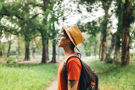 Photo for Hiker with hat holding a backpack in the forest. - Royalty Free Image