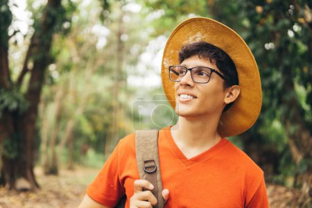Foto de Retrato de hombre latinoamericano con sombrero y mochila en gafas para una buena visión mirando hacia otro lado. - Imagen libre de derechos