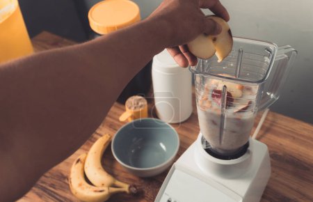Téléchargez les photos : Main tenant une pomme, préparation de smoothie au lait, banane et flocons d'avoine. - en image libre de droit