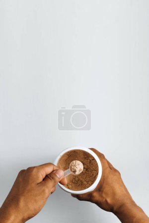 Foto de Manos sosteniendo una cucharada de proteína vegana en polvo sobre fondo blanco. - Imagen libre de derechos