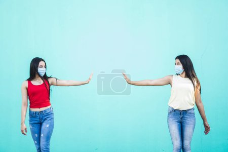 Foto de Dos mujeres jóvenes con máscaras que mantienen su distancia, pandemia y concepto de distanciamiento social. - Imagen libre de derechos