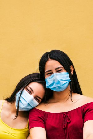 Foto de Retrato vertical de dos mujeres jóvenes con mascarillas en la cara.pandemia y nuevo concepto normal . - Imagen libre de derechos