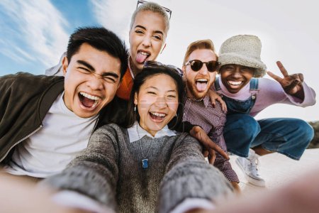 Foto de Adolescentes de raza mixta divirtiéndose disfrutando del día de verano juntos. Grupo de millonarios riéndose de la cámara - Imagen libre de derechos