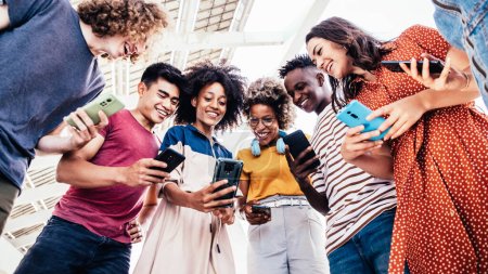 Grupo de jóvenes multirraciales que utilizan dispositivos móviles inteligentes al aire libre. Adolescentes adictos a la tecnología de redes sociales
