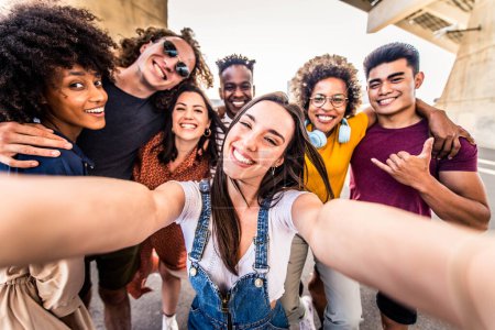 Foto de Amigos felices multiculturales divirtiéndose tomando retrato de autofoto en grupo en la calle de la ciudad. concepto de estilo de vida feliz - Imagen libre de derechos