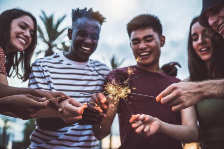 Téléchargez les photos : Jeunes multiraciaux célébrant avec des feux d'artifice. Bon style de vie, vacances, événement et concept de célébrations - en image libre de droit