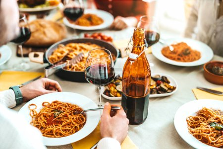 Téléchargez les photos : Heureux les jeunes gens mangeant de la nourriture italienne traditionnelle ensemble. Concept de style de vie des aliments et boissons - en image libre de droit