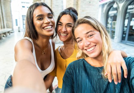 Foto de Amigos femeninos multiculturales divirtiéndose en vacaciones colgando al aire libre. Amistad y concepto de estilo de vida feliz - Imagen libre de derechos