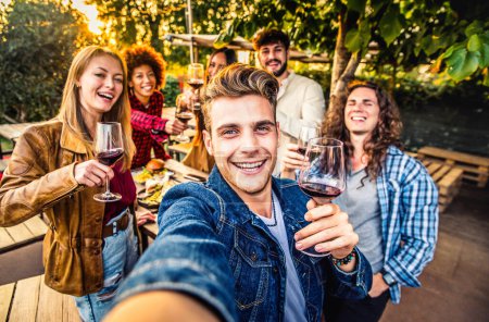 Téléchargez les photos : Les jeunes se refroidissent à l'extérieur en mangeant et buvant du vin rouge sur terrasse terrasse maison. Concept d'amitié alimentaire et jeunesse - en image libre de droit