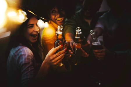 Téléchargez les photos : Groupe de jeunes multiraciaux buvant une bouteille de bière à la brasserie pub garden - Concept de style de vie avec les gars et les filles suspendus à l'extérieur - en image libre de droit