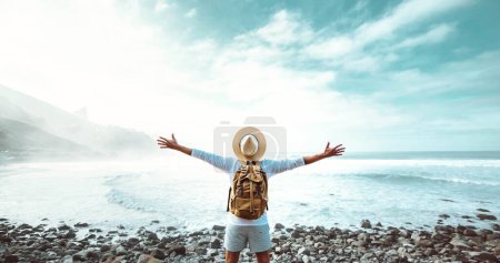 Téléchargez les photos : Homme heureux avec les bras tendus debout à l'extérieur - Délicieux voyageur avec sac à dos profiter voyage d'été - Personnes réussies, bien-être et concept de style de vie de voyage - en image libre de droit