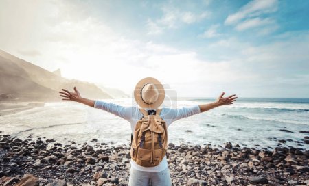 Téléchargez les photos : Heureux touriste avec sac à dos jouissant de la liberté lever les bras - concept de bien-être, voyage et tourisme - en image libre de droit