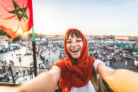Foto de Feliz turista visitando el mercado de Jamaa el-Fna, Marruecos - Hermosa mujer tomando selfie disfrutando de vacaciones de verano afuera - Concepto de vacaciones y blogger de viajes - Imagen libre de derechos