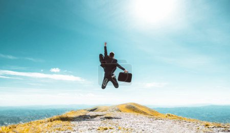 Photo for Excited young businessman jumping keeping arms raised hiking the mountain peak - Celebrating success, winner and leader concept - Royalty Free Image
