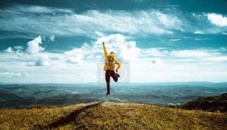 Foto de Caminante con mochila levantando las manos saltando en la cima de una montaña - Hombre exitoso con los brazos arriba disfrutando de la victoria - Concepto de deporte y éxito - Imagen libre de derechos