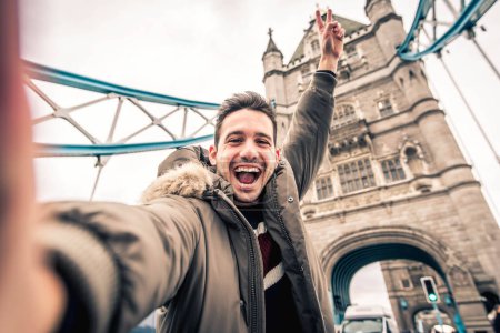 Foto de Hombre sonriente tomando retrato de selfie durante los viajes en Londres, Inglaterra - Joven turista tomando fotos de vacaciones con emblemático punto de referencia en Inglaterra - Gente feliz vagando por Europa concepto - Imagen libre de derechos