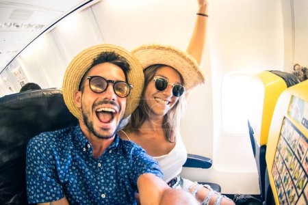 Photo for Crazy and happy young couple man and woman take selfie with smart phone on the airplane during flight - Concept about travel, lifestyle love and happiness - Royalty Free Image