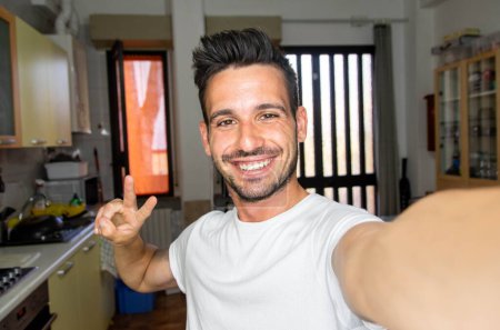 Téléchargez les photos : Bel homme caucasien prenant un portrait selfie à l'intérieur à la maison - gars heureux souriant à la caméra - concept Lifestye - en image libre de droit