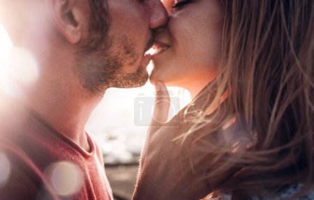 Photo for Romantic couple in love kissing at sunset - Boyfriend and girlfriend having a romance kiss outdoor - Warm filter - Royalty Free Image