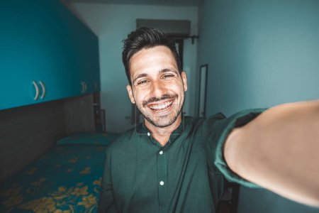 Photo for Young man taking selfie at home - Photo of handsome guy in living room enjoy weekend - Male dressed casual in video call laughing at camera - Royalty Free Image
