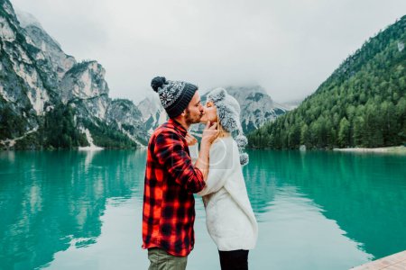 Photo for Couple of tourists visiting an alpine lake in Braies, Italy. Boyfriend and girlfriend kissing over a pier on a wanderlust background - Blue vintage filter. - Royalty Free Image