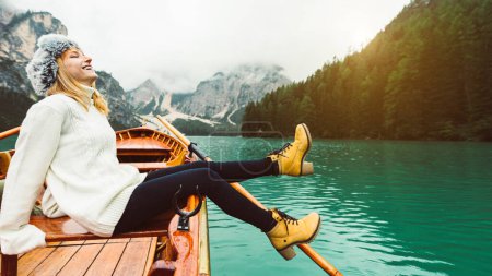 Téléchargez les photos : Femme touristique en bateau à rames en bois traditionnel sur le lac italien des Braies - Fille bénéficiant d'une vue imprenable sur le lac des Braies dans les Dolomites, Tyrol du Sud, Italie, Europe. - en image libre de droit