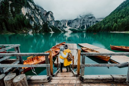 Foto de Senderistas que visitan el Lago Braies alpino italiano - Pareja enamorada disfrutando de impresionantes vistas del Lago di Braies en Dolomitas, Tirol del Sur, Italia, Europa. - Imagen libre de derechos