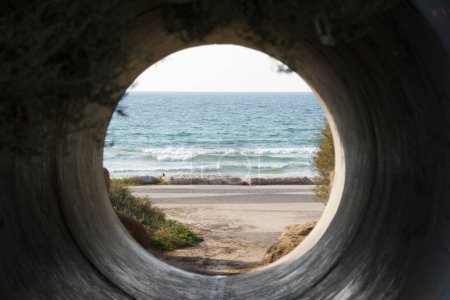 Photo for A unique perspective of Tel-Aviv's beach, framed by the circular shape of a concrete tube. - Royalty Free Image