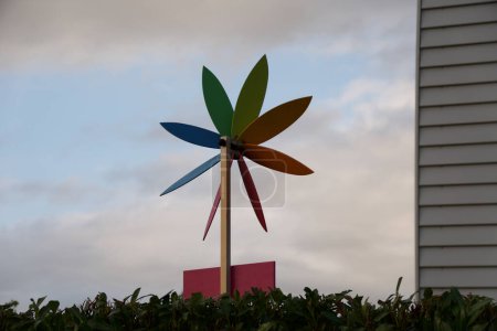 Photo for A vivid pinwheel toy stands out with its colorful blades against a soft cloudy sky, evoking a sense of childhood nostalgia. - Royalty Free Image