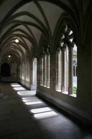 Téléchargez les photos : Lumière et ombre dansent à travers les arches gothiques d'un cloître suisse serein, évoquant un sens de la profondeur historique et de la beauté architecturale. - en image libre de droit